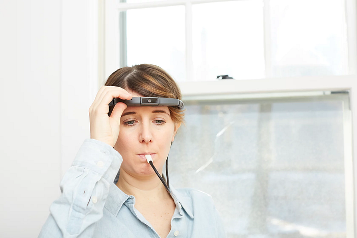 Molyneux’s Problem — Can You Really Solve This Challenge? — An image of a woman using BrainPort Vision Pro. Here’a headset with a camera seems to be connected by a wire to electrodes that are placed by the subject in their mouth (on the tongue).