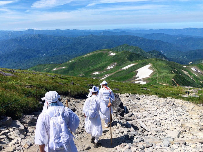 Tim Bunting AKA The Kiwi Yamabushi leading Yamabushi training on Mt. Gassan of the Dewa Sanzan. In the background is Mt. Ubagatake and Mt. Yudono
