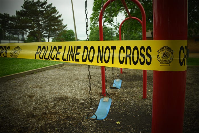 Yellow police caution tape across playground.
