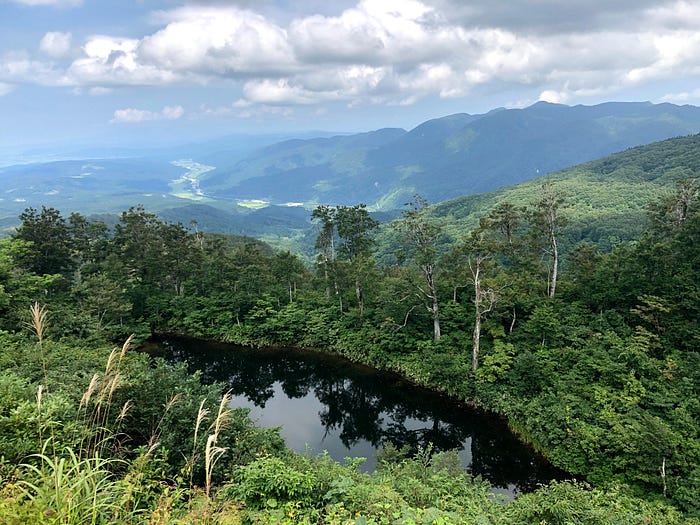 A mountain lake on Mt. Gassan of the Dewa Sanzan with a river valley in the background