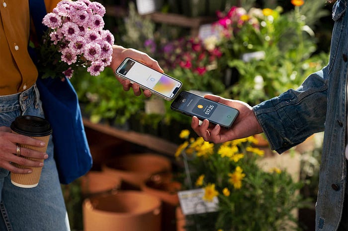 A customer uses Tay to Pay on iPhone to buy plants at the farmer’s market.