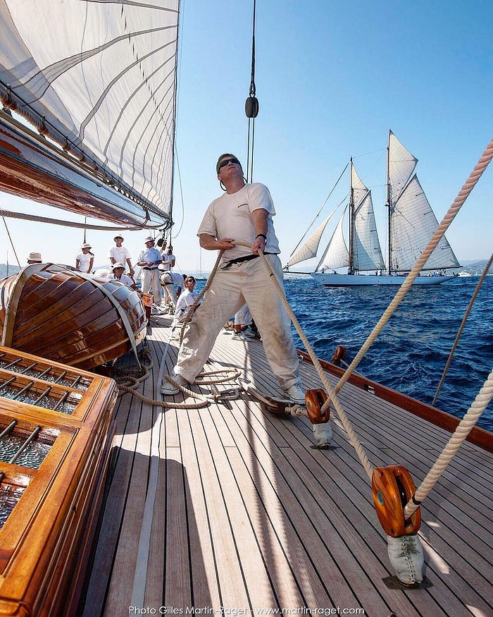 a sailor on the deck of an old sailing ship, pulling a sail sheet