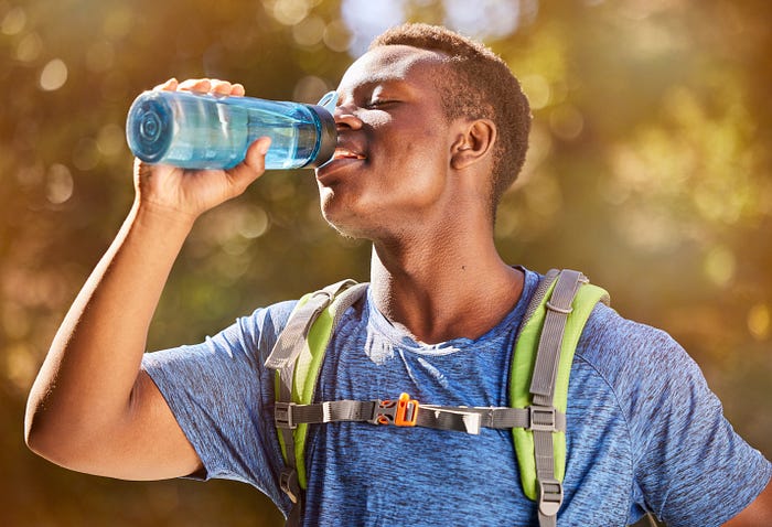 A young man wearing a hydration vest and drinking out of a portable water bottle, Hydration Pack Lifestyle, Hydration Pack Adventure, Hydration Pack Life, Hydration Pack Love, Hydration Pack Nation