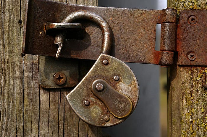 IMAGE: An open, very old and rusty padlock on a door