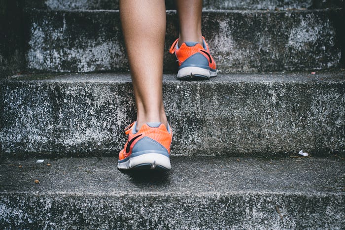 Woman from the calves down walking up stone steps in running shoes