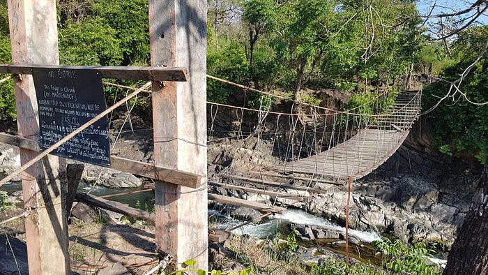 Photo of a broken down bridge; the sign claims maintenance to be ongoing