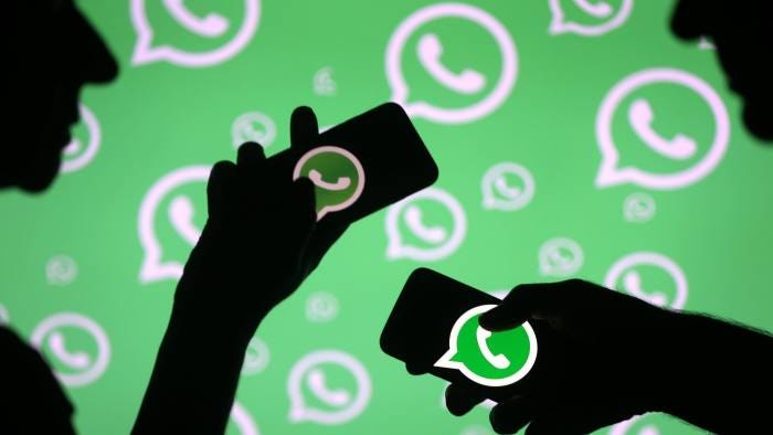 Illustration of two silhouettes of people with their smartphones on their hands where we can see the Whatsapp application logo in each one of it.