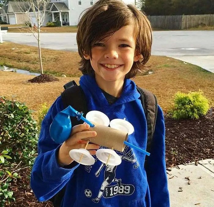 A kid holding Balloon-powered toilet roll with wheels