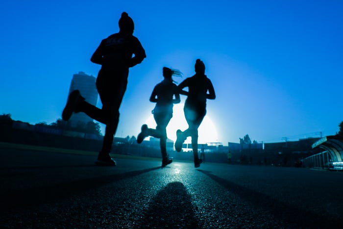Women running outside early in the morning with shadows around them