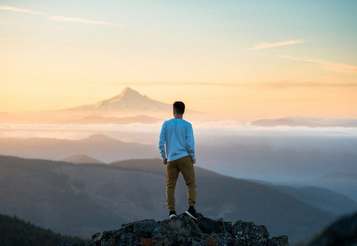 A person standing on a mountain at sunset.