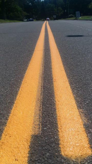 Double yellow lines running down the center of the road, into the distance