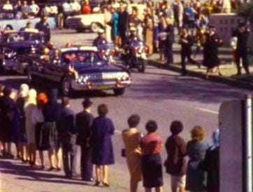 A frame of the Zapruder Film showing JFK’s car and the crowd attending just before he was assassinated.