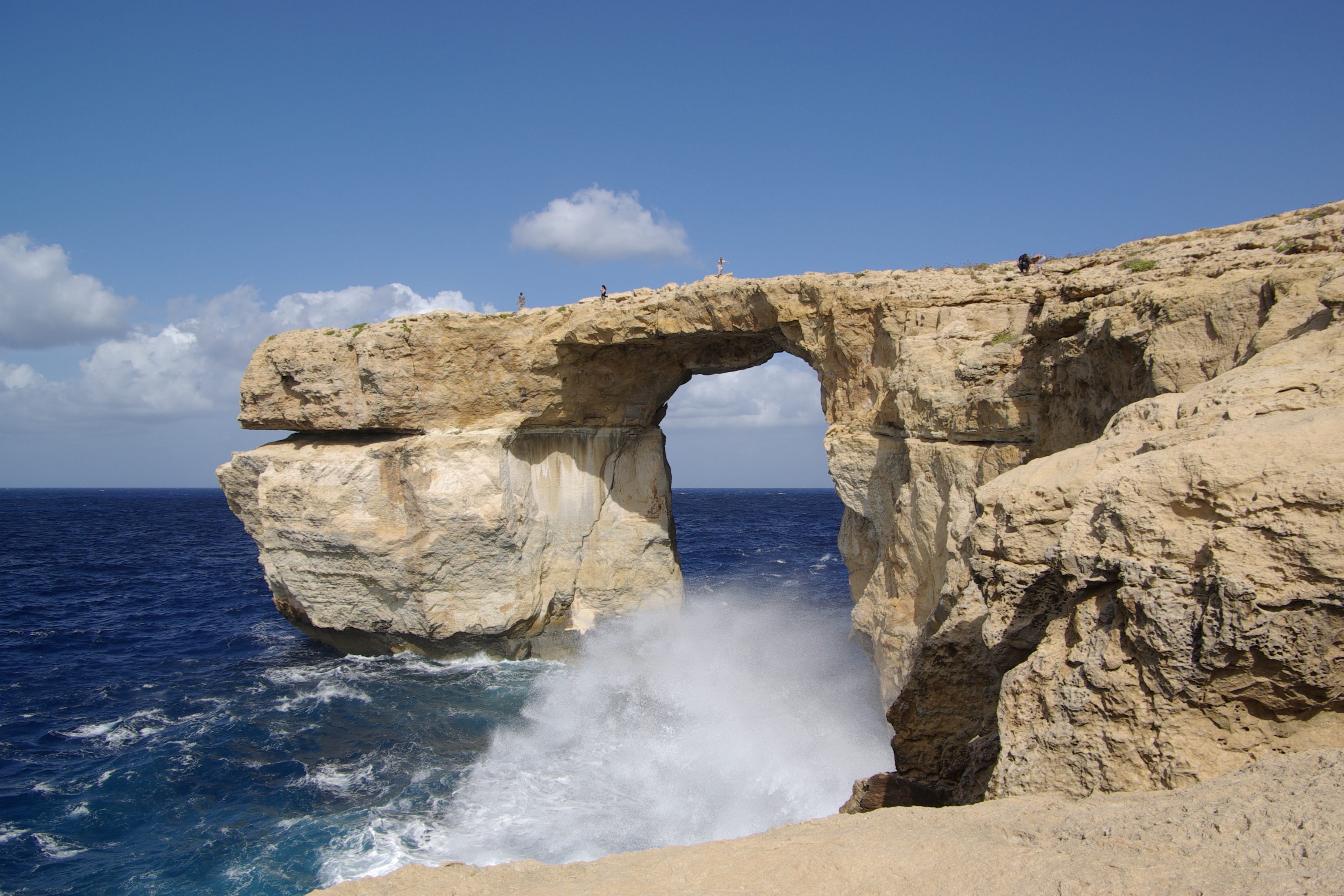 The image shows a rock feature called the Azure Window in Gozo, Malta, as waves crash against the coast.