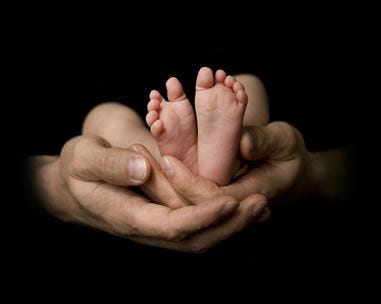 Newborn feet being held by an adults hands.
