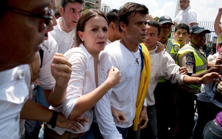 La congresista venezolana María Corina Machado, a la izquierda, y Leopoldo López, en el centro, rodeados de manifestantes antigubernamentales antes de que López se entregara a la Guardia Nacional en Caracas, el 18 de febrero de 2014. (Foto: AP / Juan Manuel Hernández)