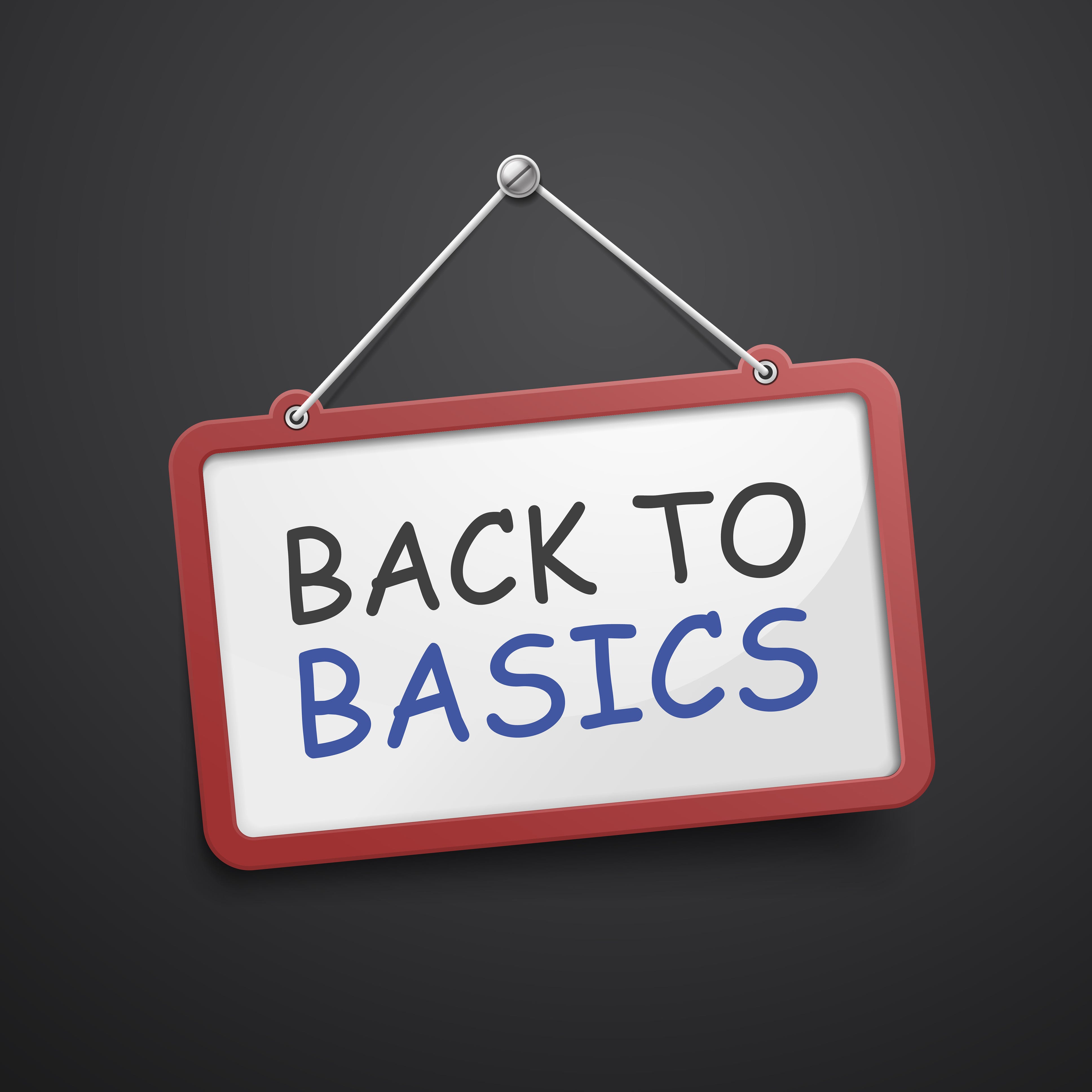 Tilted sign that says “Back to Basics” hanging on black chalkboard
