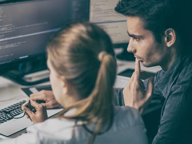 Two developers a man and a woman, are pair programming