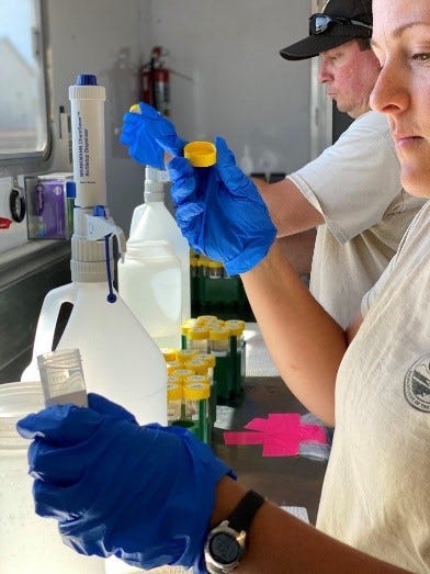 Two people holding tubes with water samples in a lab