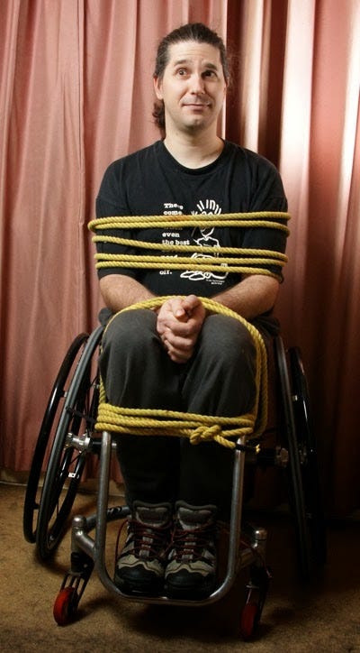 Young man in a wheelchair tied to it with a rope