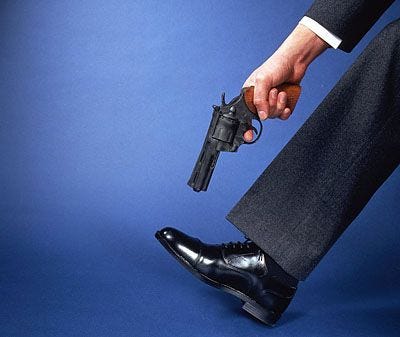 Man in suit pointing gun at well-polished shoe.