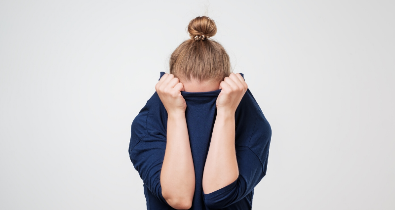 Woman hiding her face to protect herself from fear