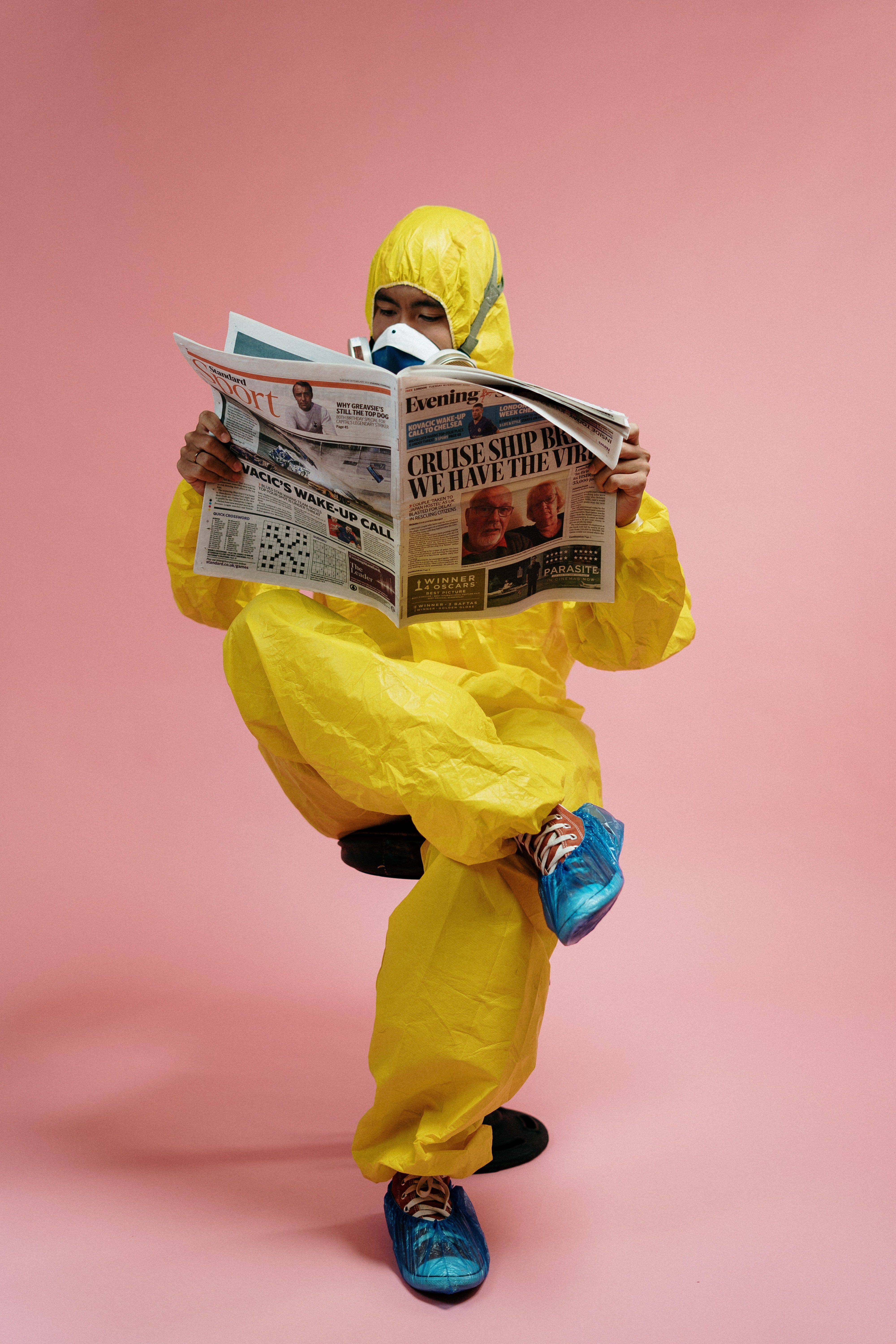 A man in a protective suit reads a newspaper