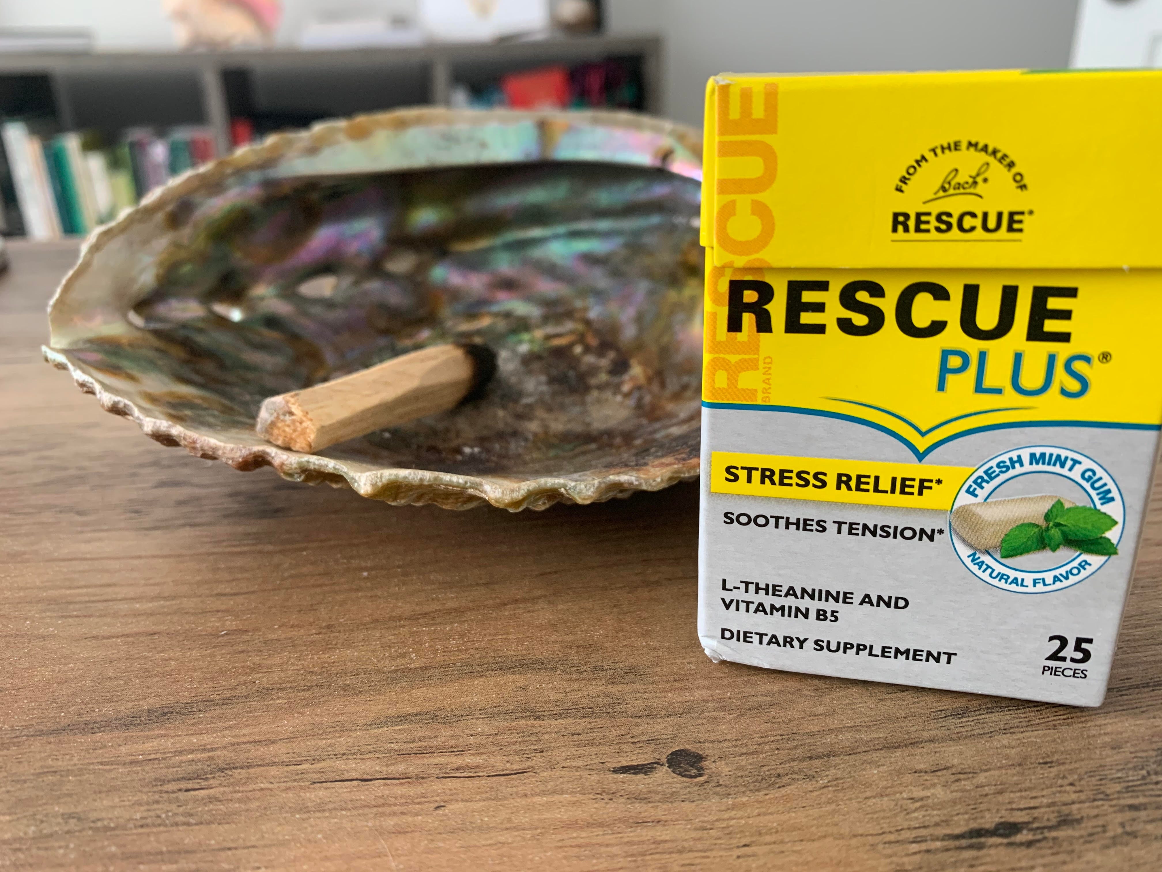 A shell with a stick of palo santo wood and a box of Bach Rescue Plus mint gum