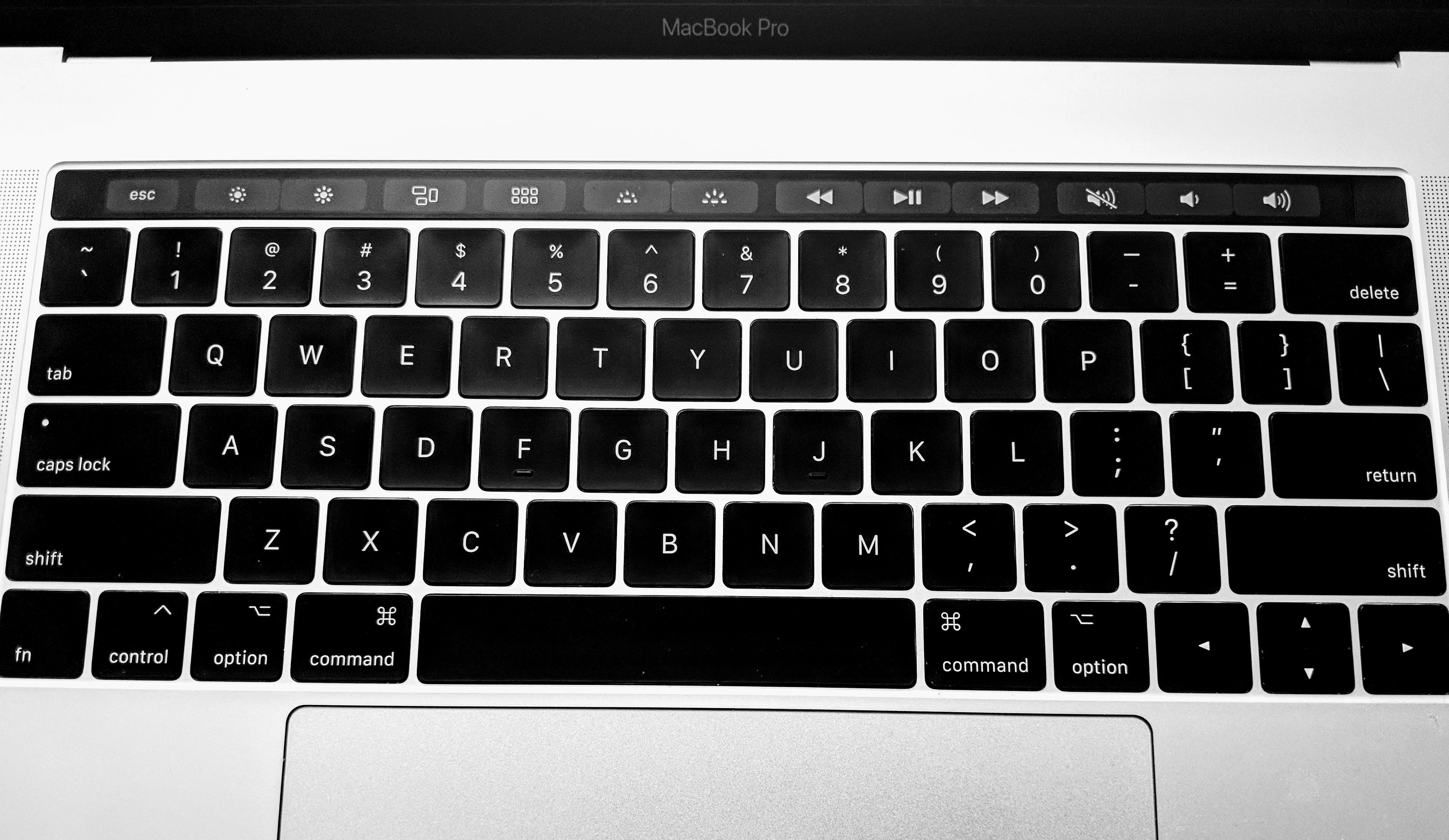 Eine MacBook-Tastatur, deren Touch Bar nur die Tasten der „erweiterten Steuerleiste“ anzeigt: Esc, Displayhelligkeit, Exposé, Launchpad, beleuchtete Tastenhelligkeit, Medientasten und Lautstärketasten.