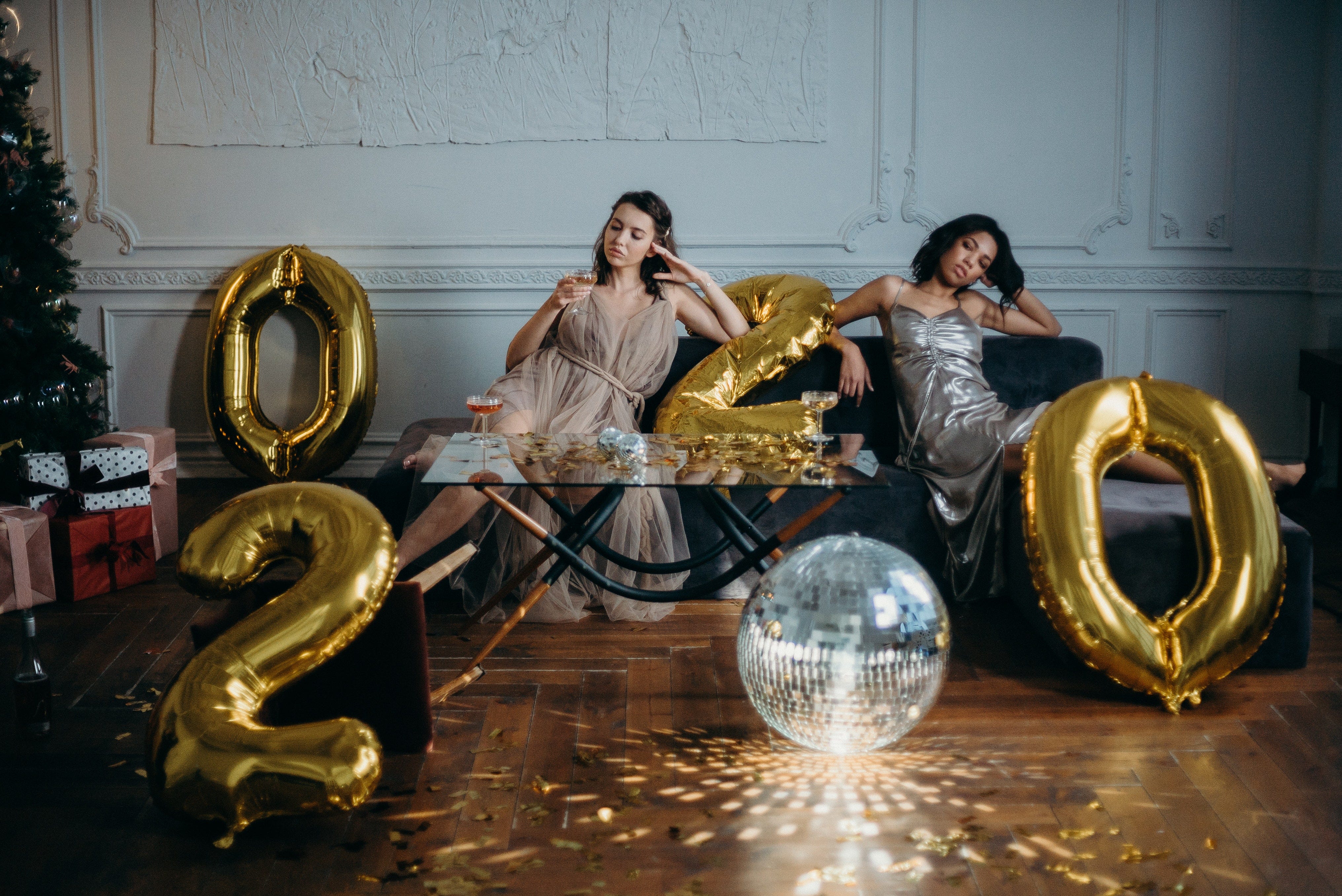Two women sitting on sofa with 2020 baloons