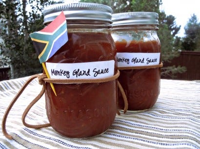 Two canning jars full of red sauce with a little paper South African flag on one of them