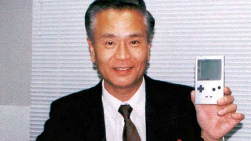 A picture of Gunpei Yokoi holding a Nintendo Game Boy.