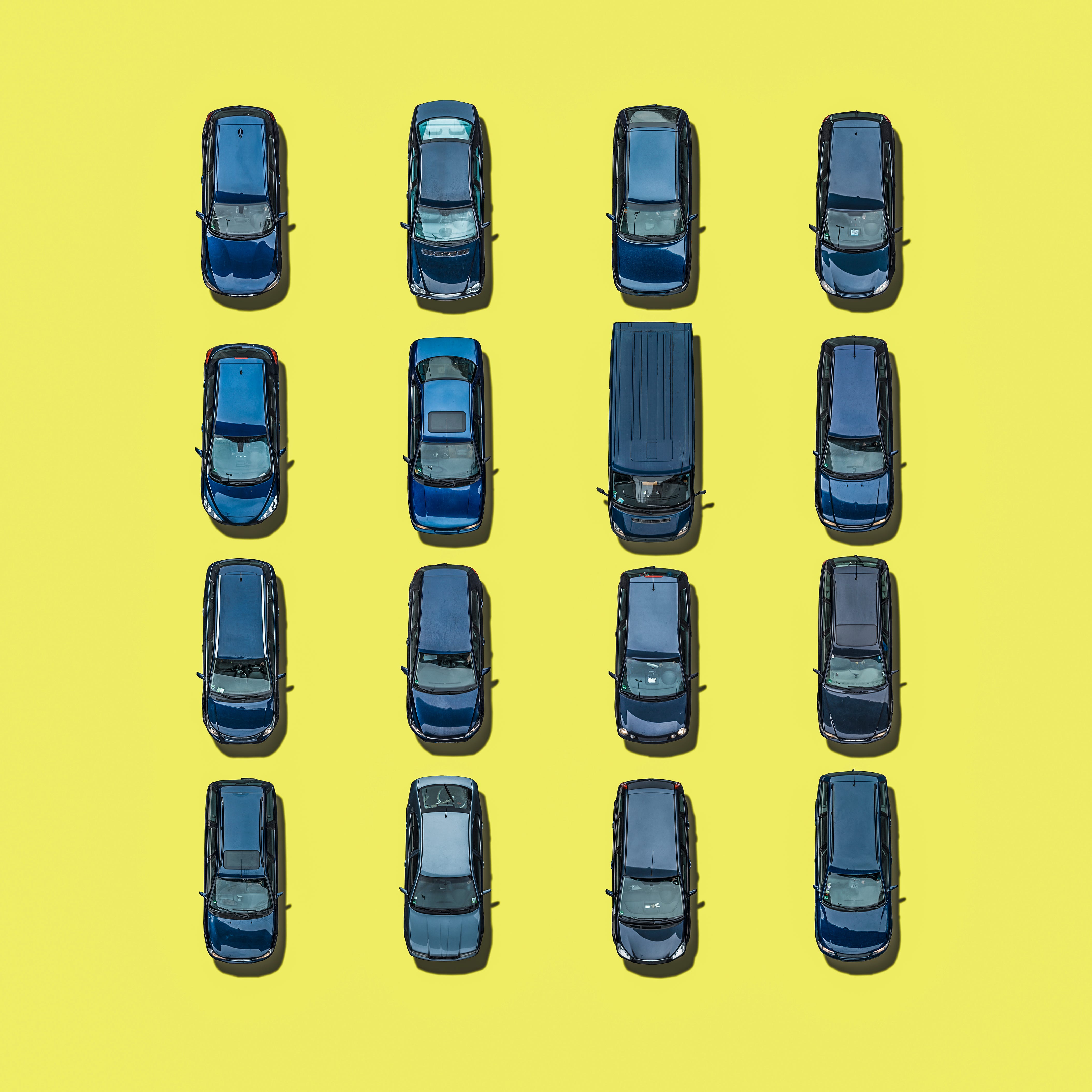 An aerial view of 16 blue cars on yellow background.