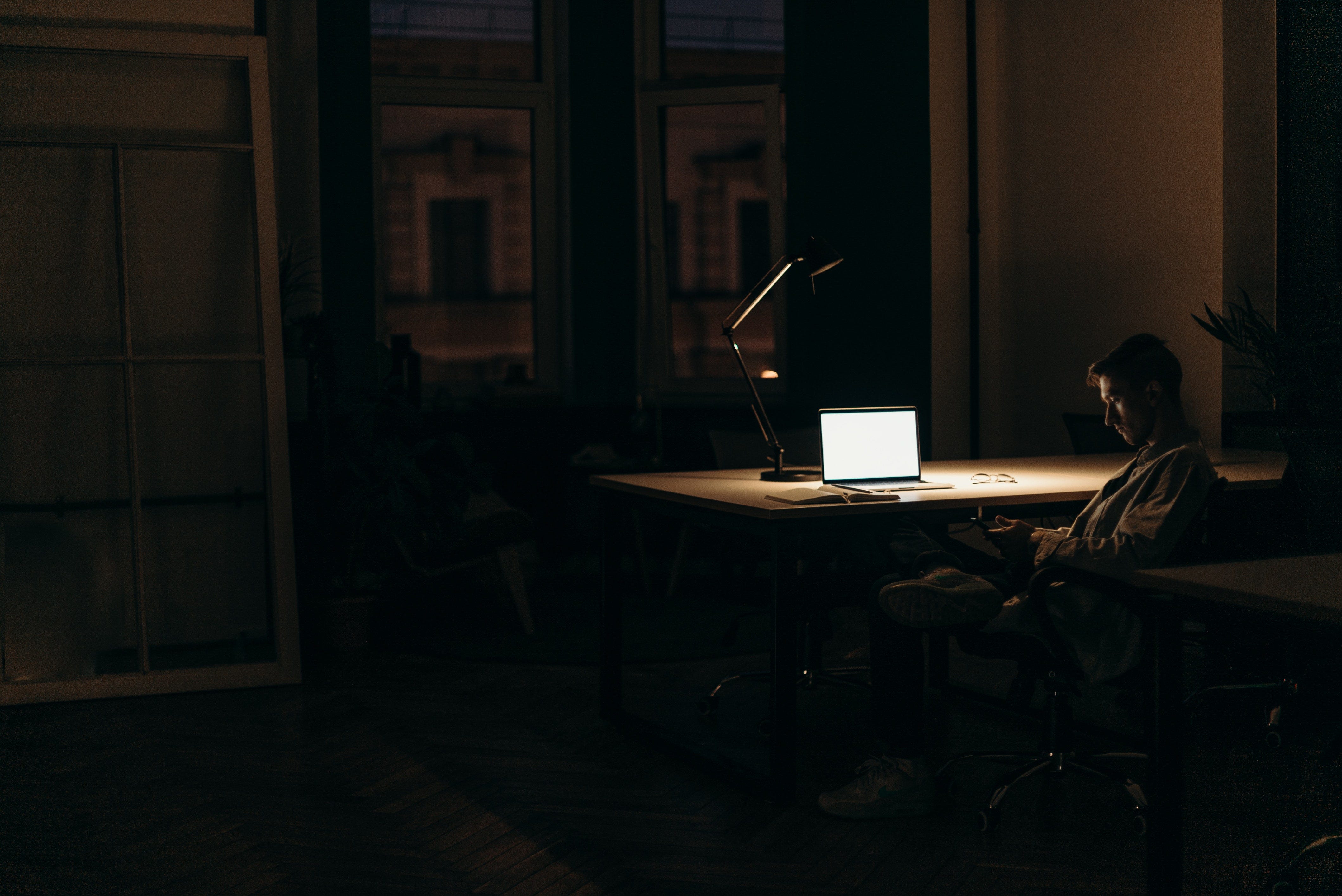 A man sits in the dark; his devices his only sources of comfort. The loneliness shrouds him together with the darkness.