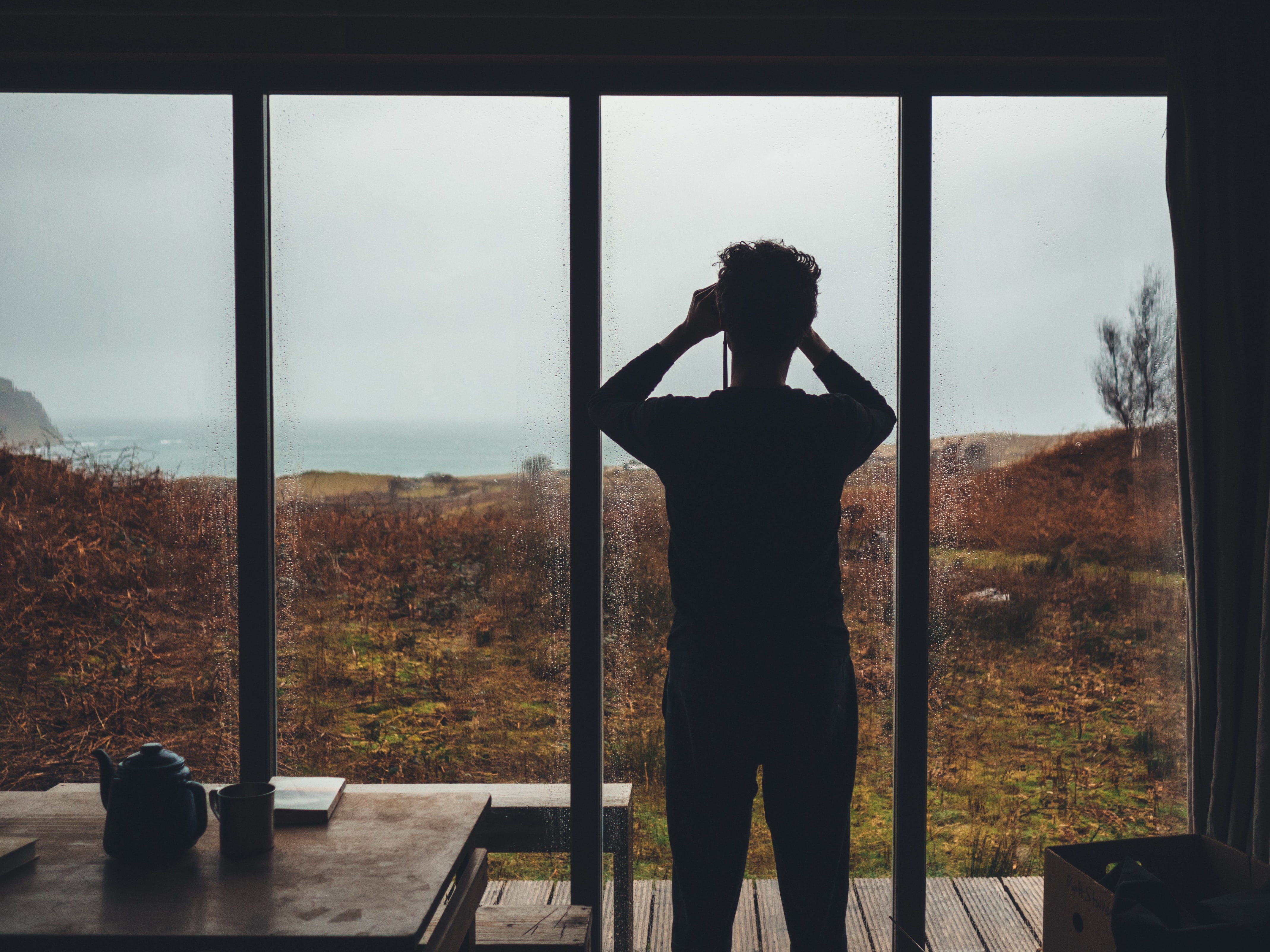 Man inside house looking through binoclears through sliding glass doors into a wide expanse of open space