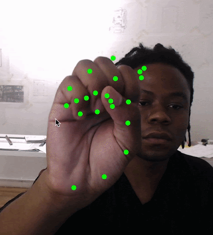 A person opens and closes their hand in front of a camera. Green dots are drawn over key positions on their palm and fingers.