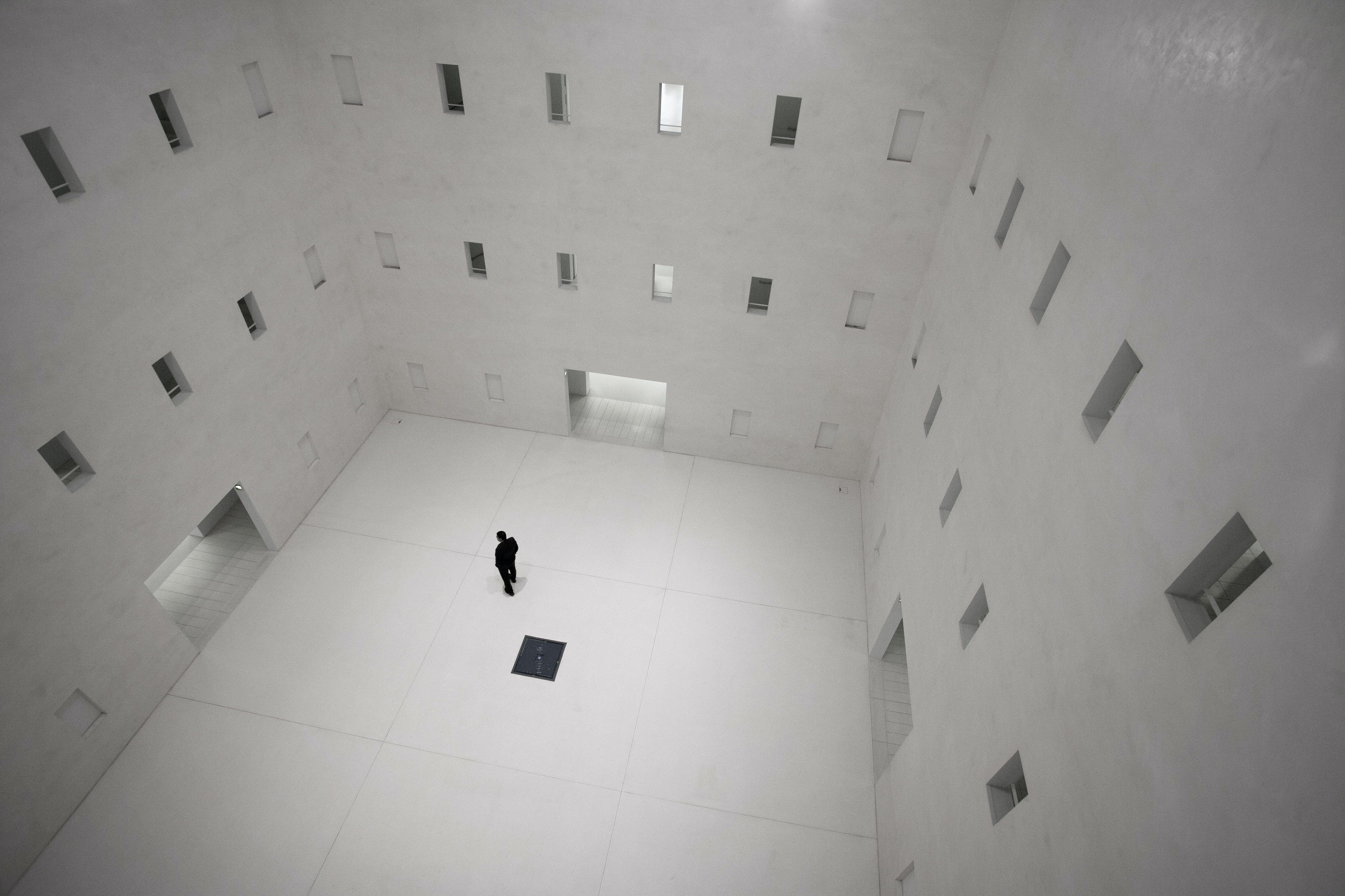 Man in a white room surrounded by numerous doors & window openings