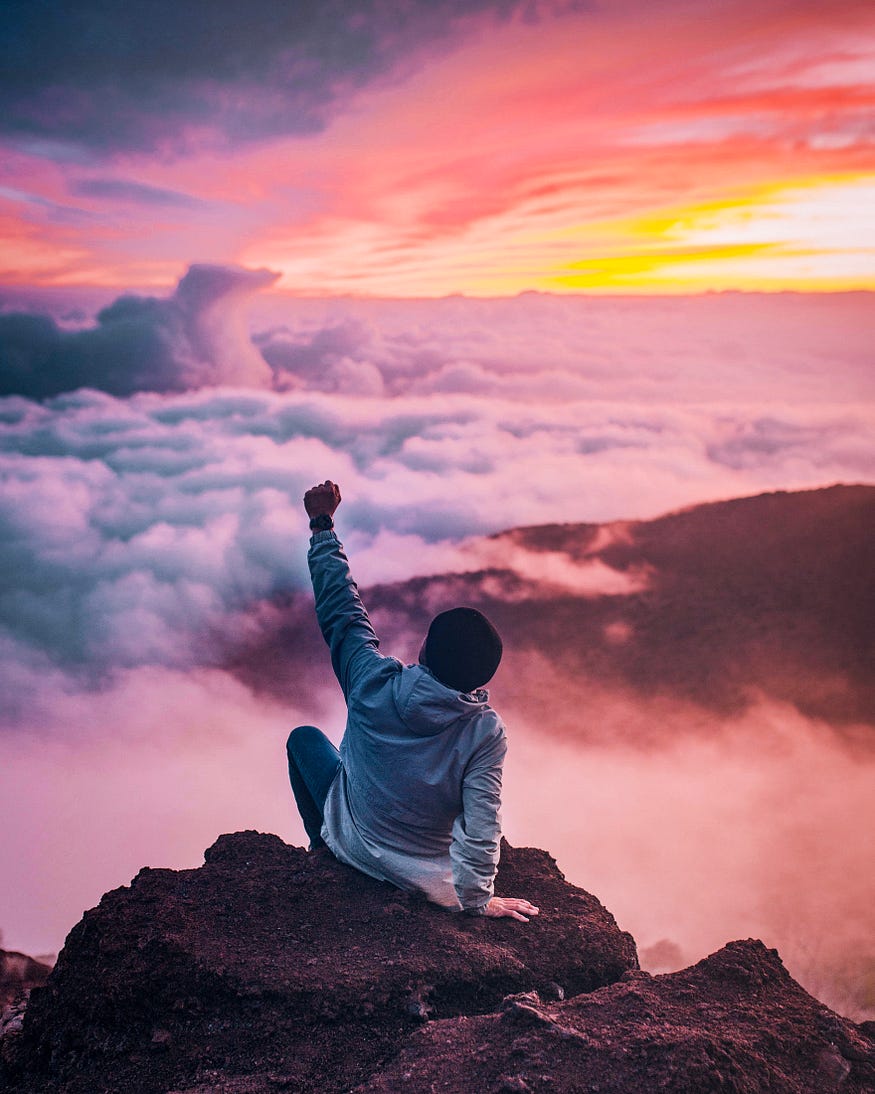 Man pumping his fist towards the sky which has puffy clouds