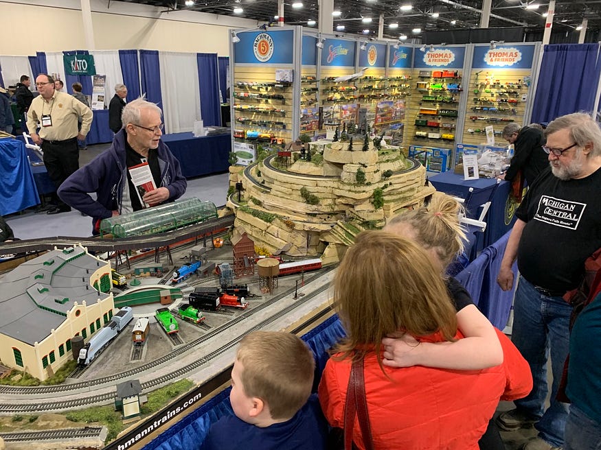 A few onlookers taking in a model train show.