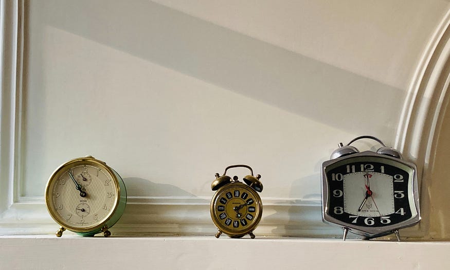 three old-fashioned alarm clocks on a shelf