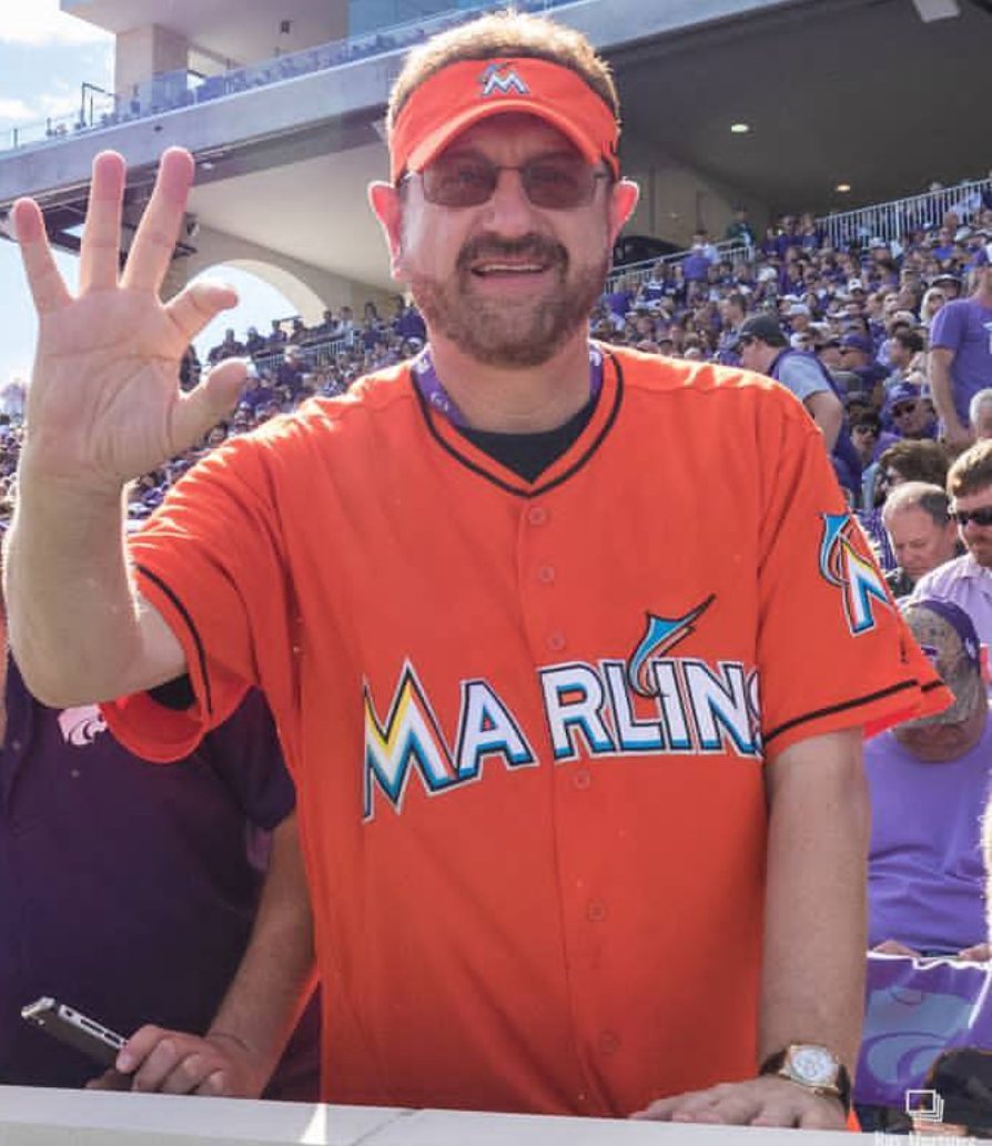 man in marlins jersey at baseball games