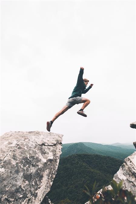 A man jumping over two mountaind.