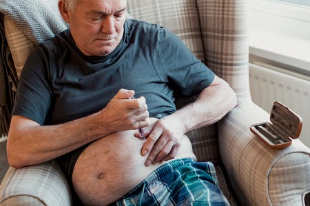 An elderly man delivers insulin using an insulin pen