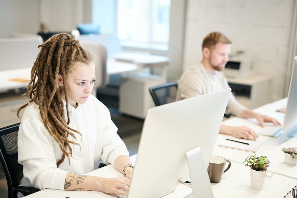 A woman and man work in front of their computers