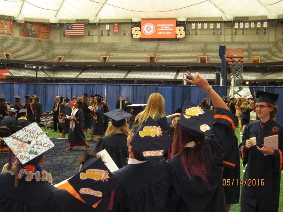 people at graduation in cap and gown, with out there productions logo on the caps