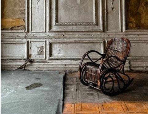 Empty wooden rocking chair in wood-paneled empty apartment