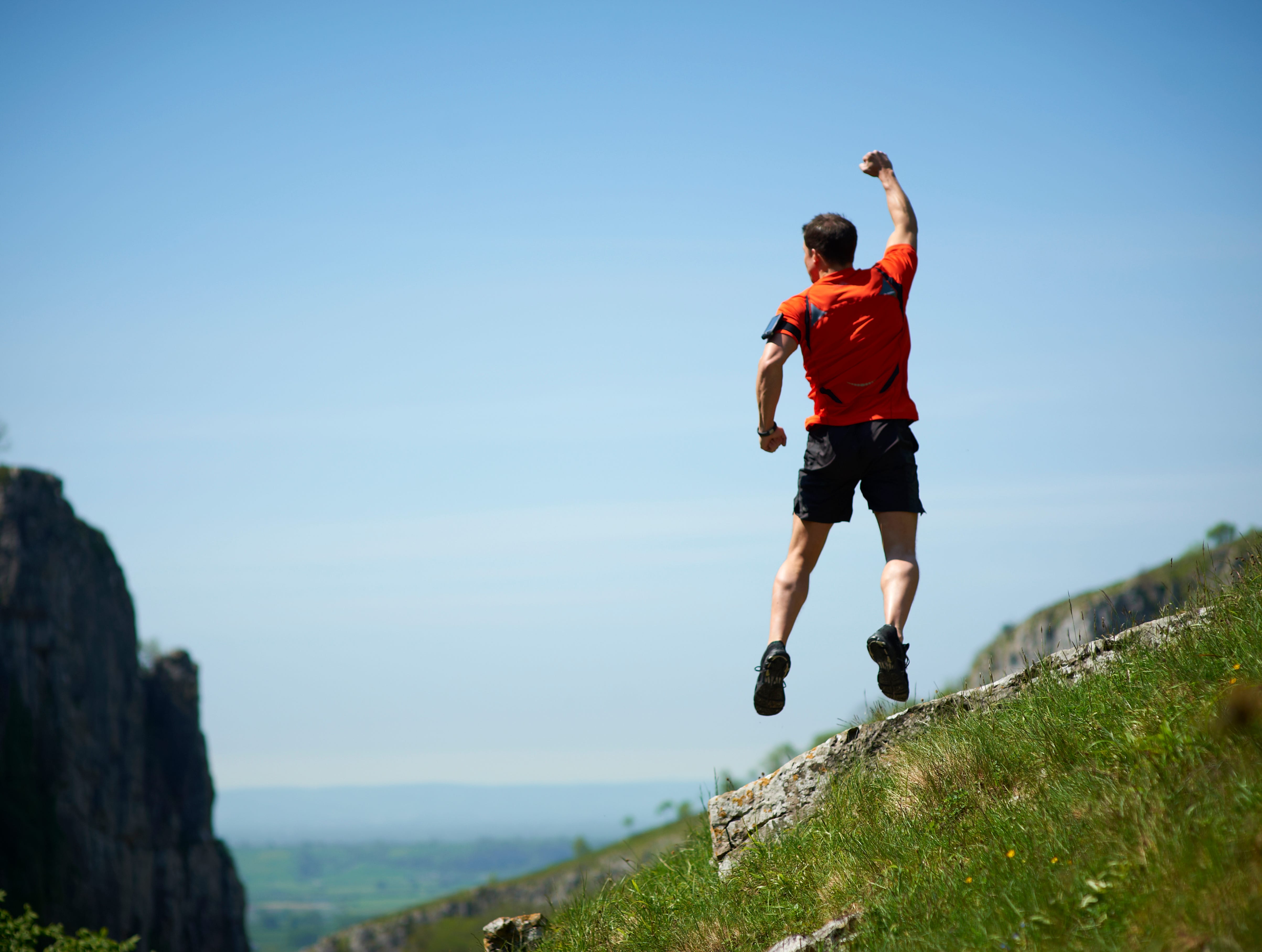 A male mountain runner is jumping up and punching the air.