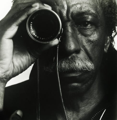 Elderly Gordon Parks holding a camera lens up to his eye