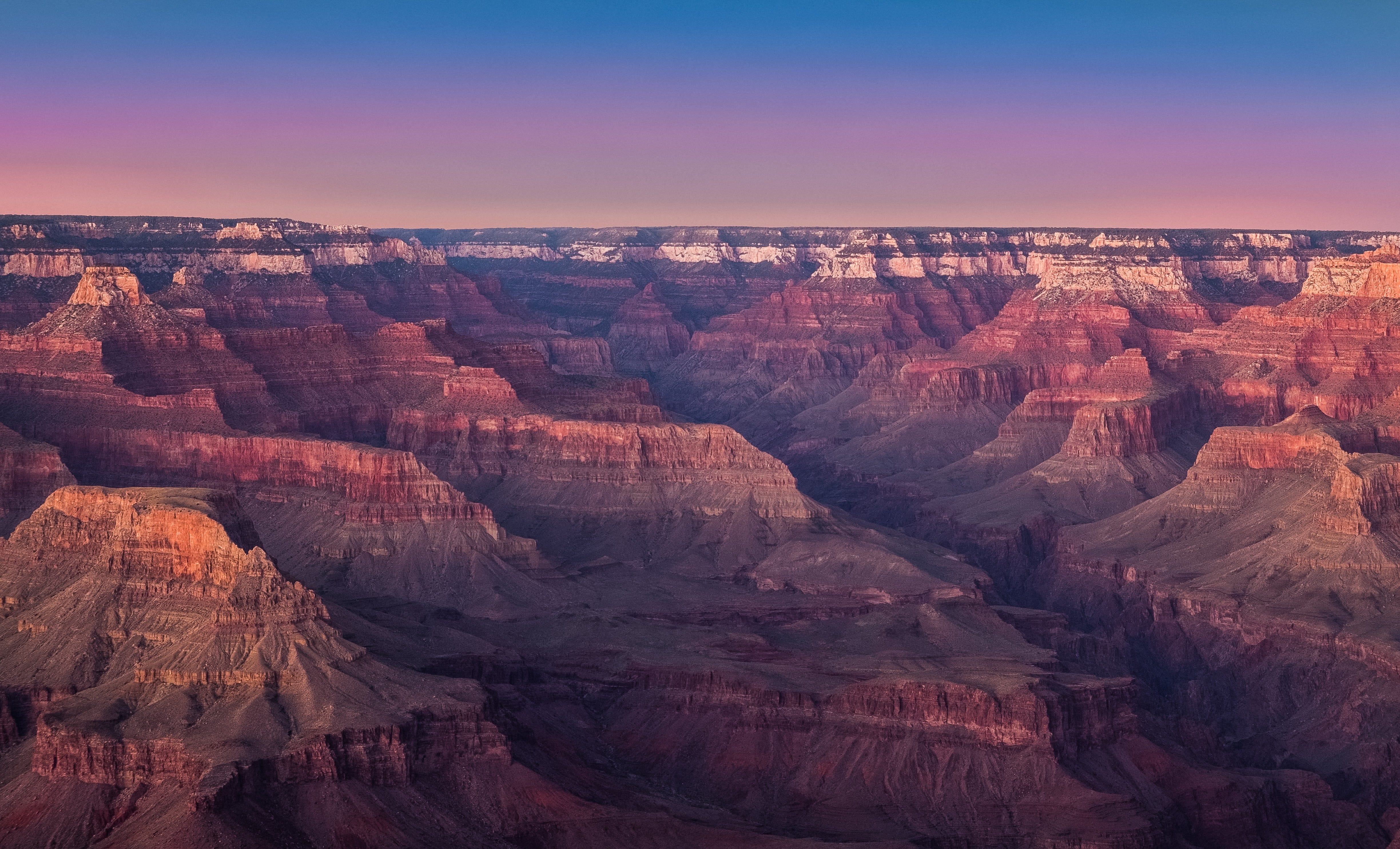 Arial view of the grand canyon — flat topped mountains with striated sandstone in oranges and browns with a river