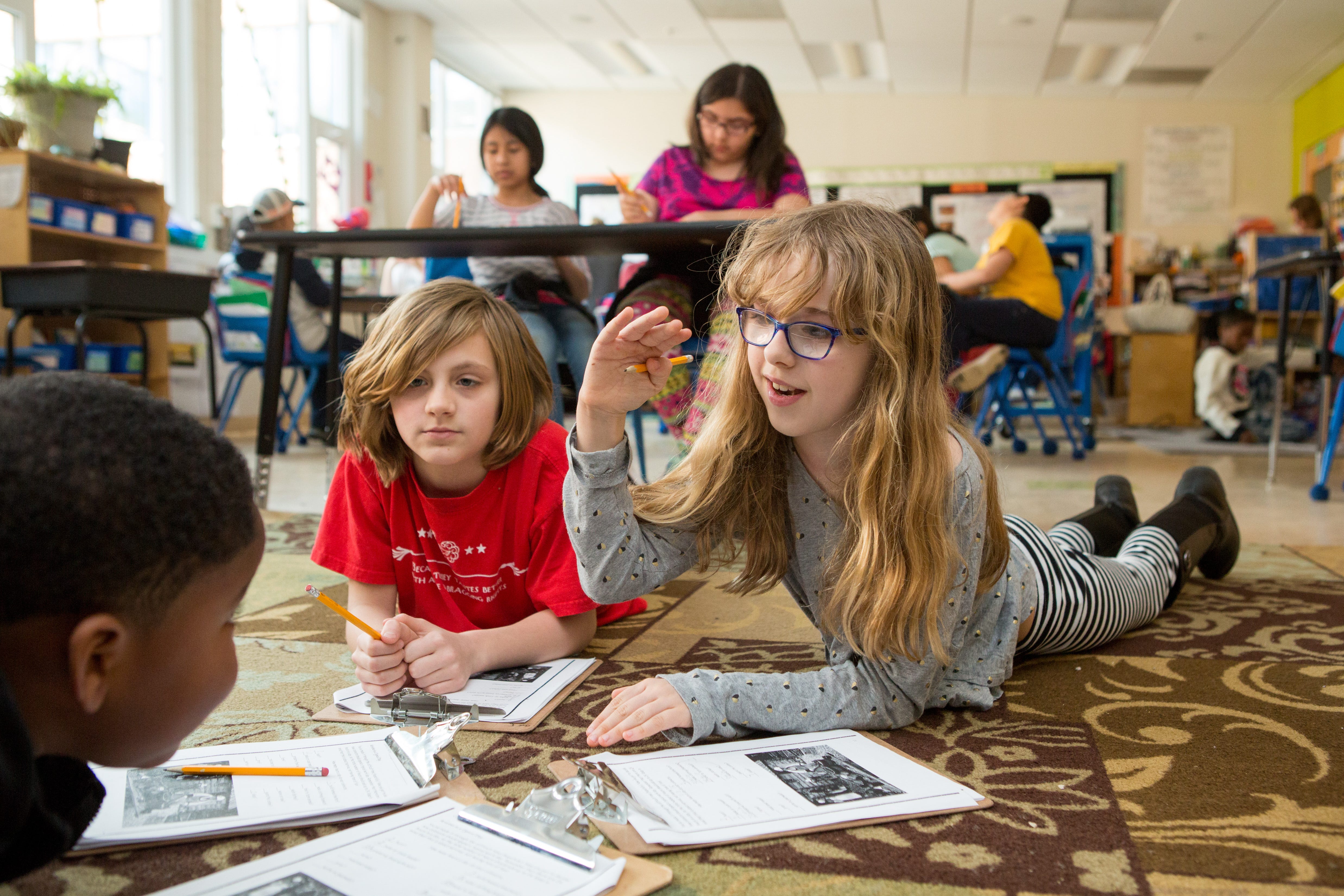 Three students work together in a classroom.