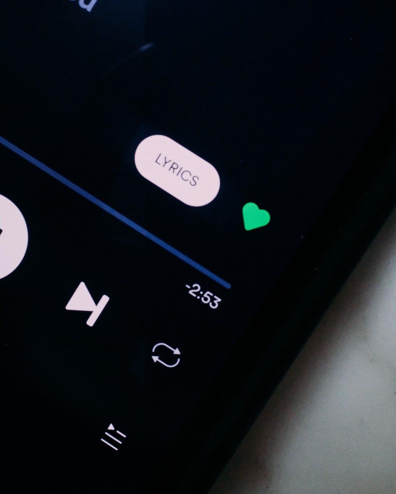 A closeup of a smatphone playing a song on spoitfy.